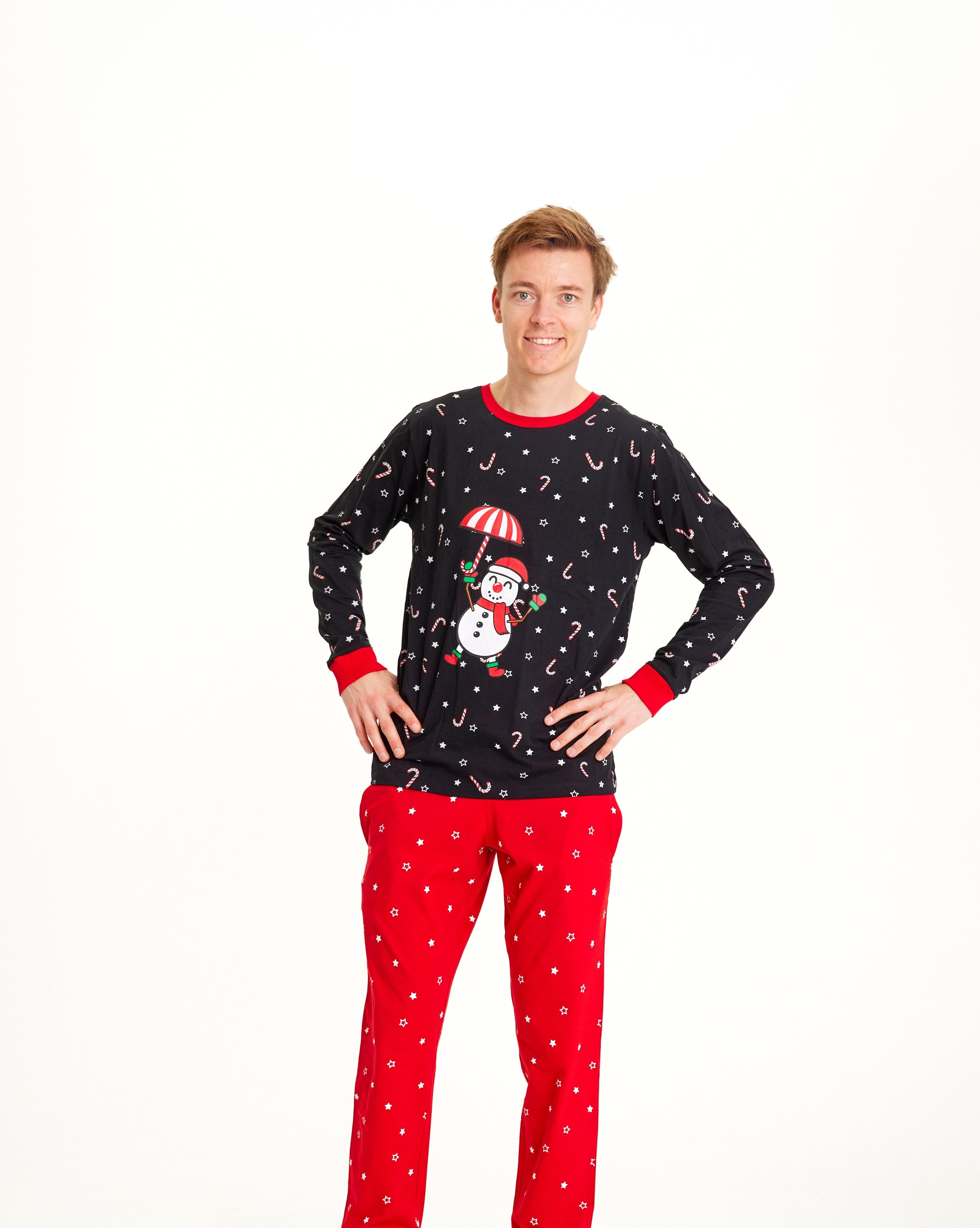 En mann poserer iført svart og rød julepyjamas med snømann på.